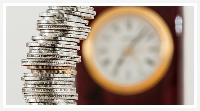 Stack of coins in front of a clock