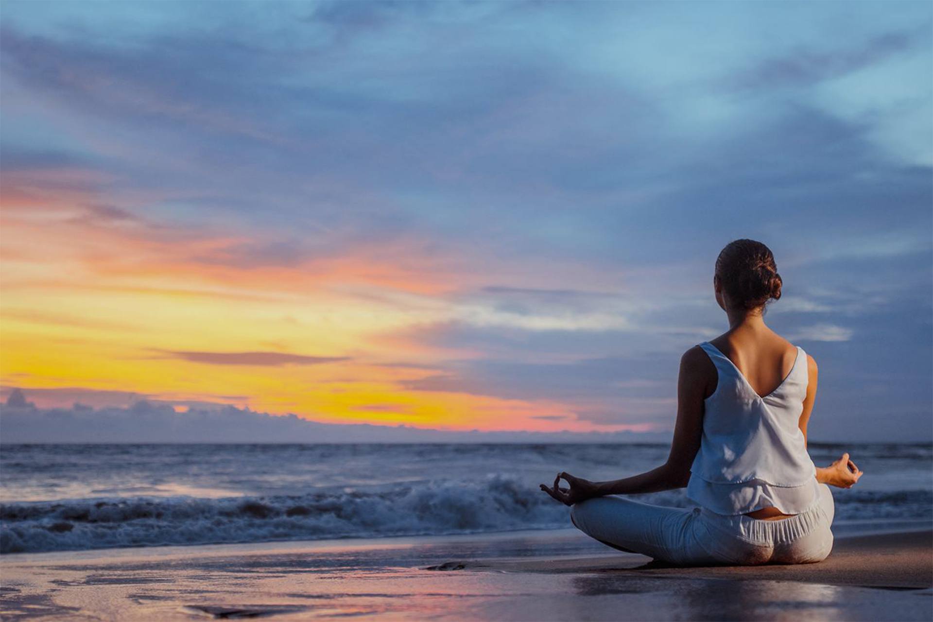 Young woman sitting in lotus position on the beach