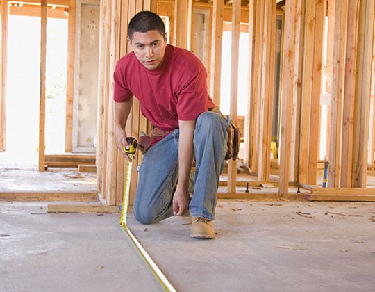Construction worker measuring with tape measure