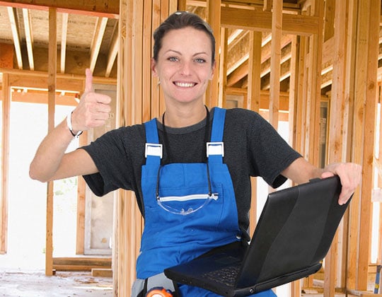 Construction worker holding a laptop and giving a thumbs up