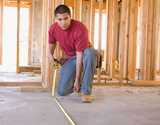 Construction worker measuring with a tape measure
