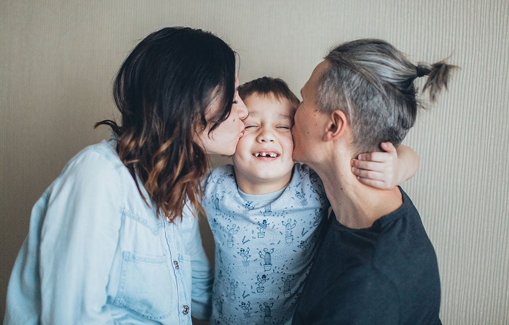 Family kissing their child