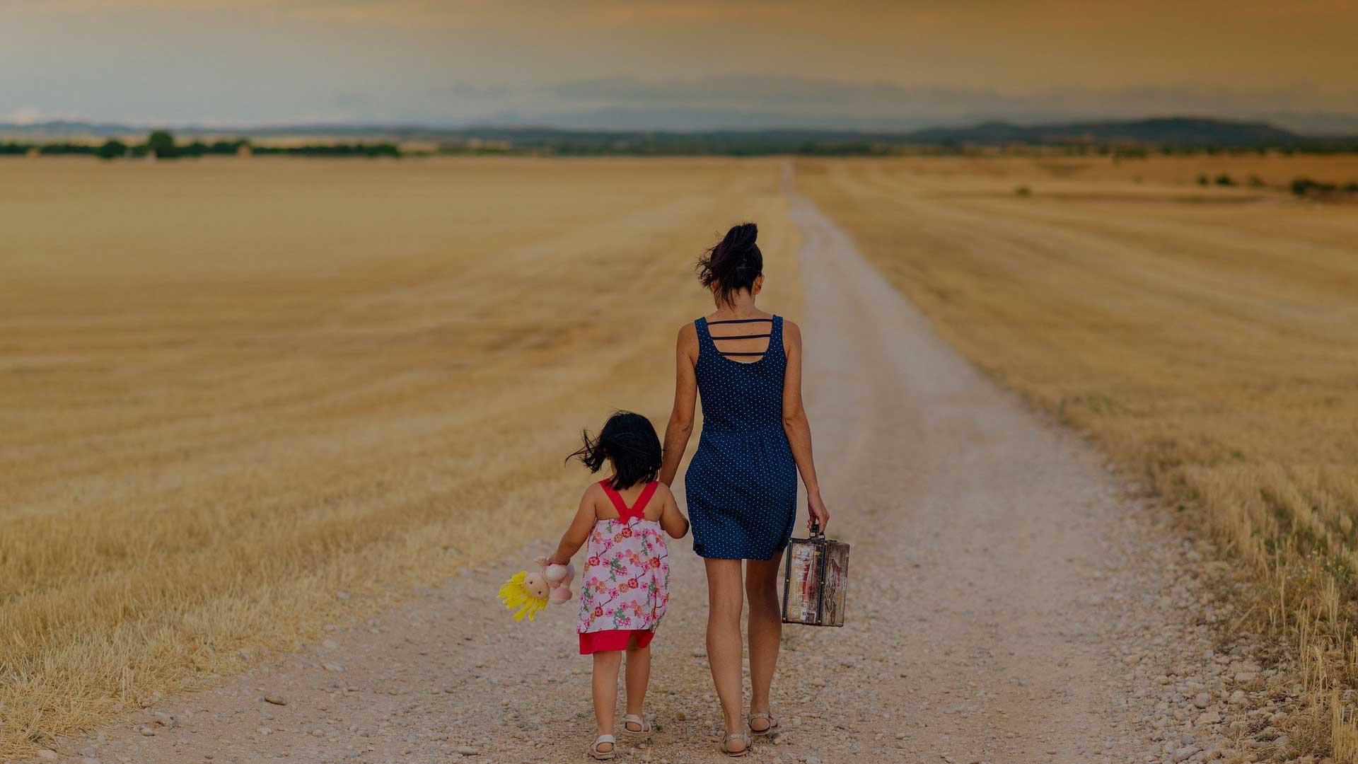 Woman and child walking down a dirt road