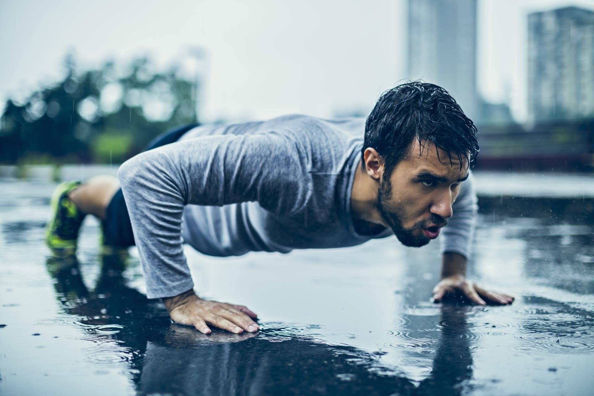 Young athletic man exercising in the rain