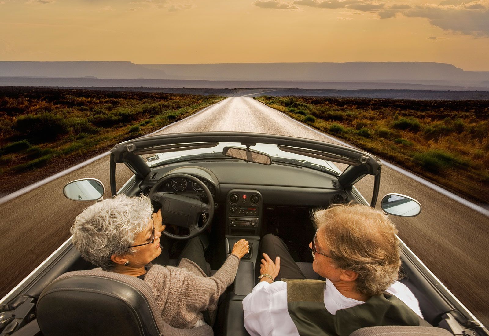 Elderly couple driving a convertible car