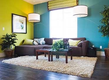 Living room with dark wood floor, brown sofa and colourful walls