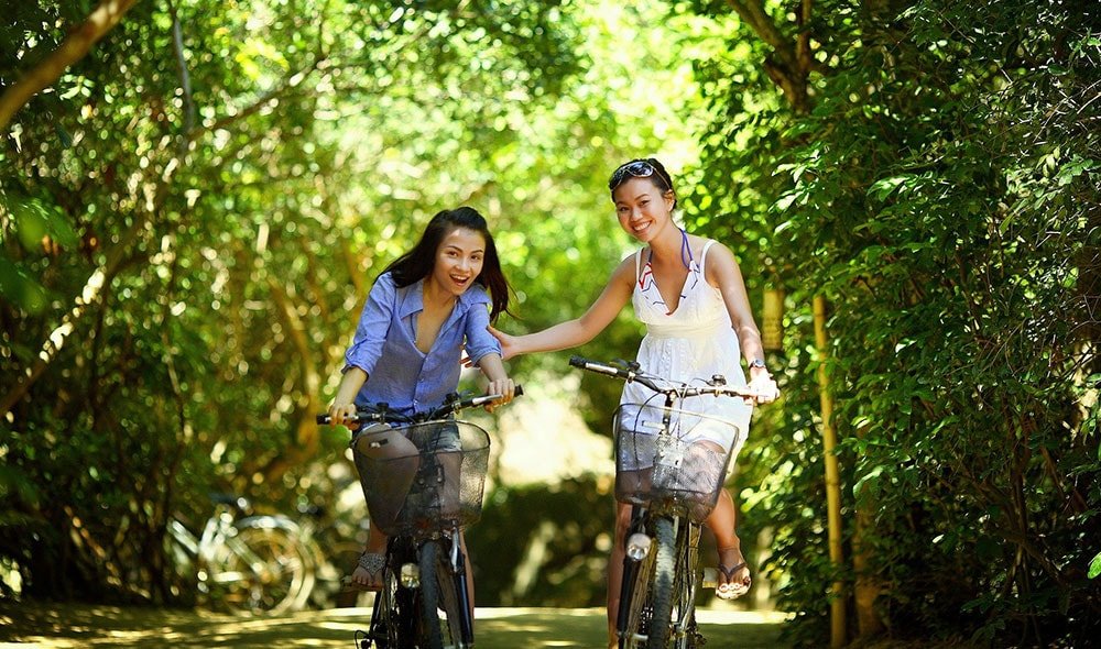 Two ladies riding bikes in a park